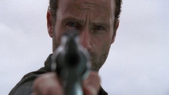 Movie still from “The Walking Dead” (2010), directed by Daniel Sackheim – A person holding a gun; Extreme Close Up shot, Low angle