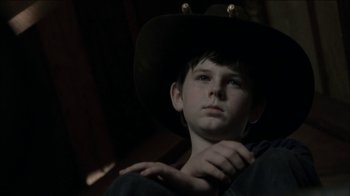 Movie still from “The Walking Dead” (2010), directed by Daniel Sackheim – A young boy wearing a cowboy hat and holding his hand on his chest; Close Up shot, Low angle