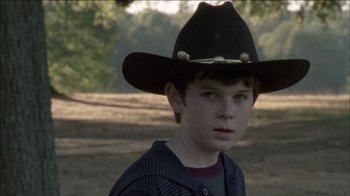 Movie still from “The Walking Dead” (2010), directed by Daniel Sackheim – A young boy wearing a cowboy hat in a dirt field; Close Up shot, Over the shoulder angle