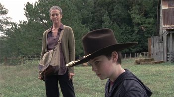 Movie still from “The Walking Dead” (2010), directed by Daniel Sackheim – A woman standing next to a young boy in a field; Medium shot, Over the shoulder angle