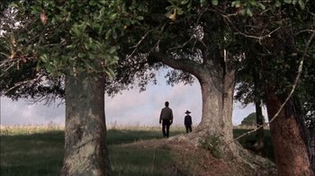 Movie still from “The Walking Dead” (2010), directed by Daniel Sackheim – Two people are walking through the trees in a field; Wide shot, Low angle