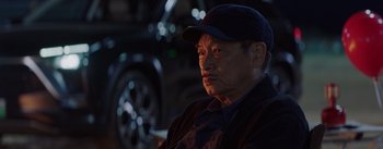 Movie still from “The Wandering Earth” (2019), directed by Frant Gwo – An older man sitting in front of a parked car at night; Close Up shot, Over the shoulder angle