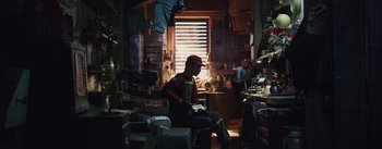 Movie still from “The Wandering Earth” (2019), directed by Frant Gwo – A man sitting on a chair in a cluttered room; Wide shot, Low angle