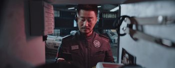 Movie still from “The Wandering Earth” (2019), directed by Frant Gwo – A man in a uniform looking at his cell phone; Close Up shot, Over the shoulder angle