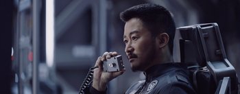 Movie still from “The Wandering Earth” (2019), directed by Frant Gwo – A man holding up a camera while wearing a black shirt; Close Up shot, Low angle