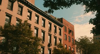 Movie still from “Can You Keep a Secret?” (2019), directed by Elise Durán – A view of a building from the side of the street; Extreme Wide shot, Low angle
