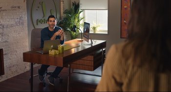 Movie still from “Can You Keep a Secret?” (2019), directed by Elise Durán – A man sitting in front of a laptop computer at a desk; Medium shot, Over the shoulder angle