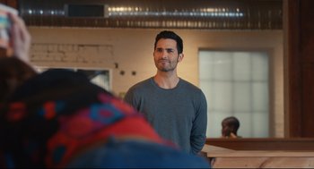 Movie still from “Can You Keep a Secret?” (2019), directed by Elise Durán – A man standing in front of another man in a room; Medium shot, Over the shoulder angle