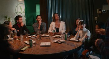 Movie still from “Can You Keep a Secret?” (2019), directed by Elise Durán – A group of people sitting around a table at a restaurant; Medium shot, High angle