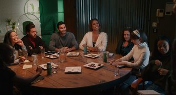Movie still from “Can You Keep a Secret?” (2019), directed by Elise Durán – A group of people sitting around a table at a restaurant; Wide shot, High angle