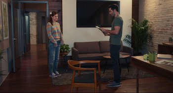 Movie still from “Can You Keep a Secret?” (2019), directed by Elise Durán – A man and a woman standing in a living room; Wide shot, Over the shoulder angle