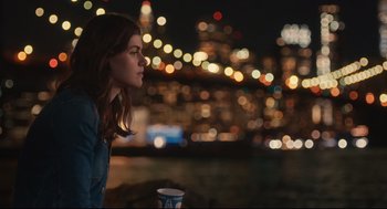 Movie still from “Can You Keep a Secret?” (2019), directed by Elise Durán – A woman sitting in front of a city skyline at night; Medium shot, Over the shoulder angle