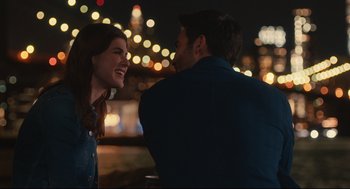 Movie still from “Can You Keep a Secret?” (2019), directed by Elise Durán – A man and a woman are smiling at each other in front of a city skyline; Medium shot, Over the shoulder angle