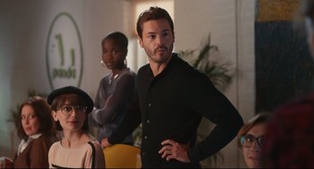 Movie still from “Can You Keep a Secret?” (2019), directed by Elise Durán – A man standing next to two other people; Medium shot, Over the shoulder angle