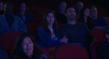 Movie still from “Can You Keep a Secret?” (2019), directed by Elise Durán – A woman and a man are sitting in a movie theater; Medium shot, High angle