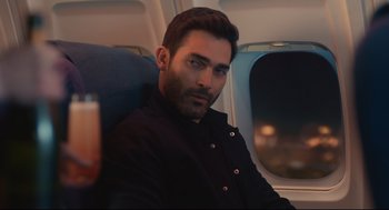 Movie still from “Can You Keep a Secret?” (2019), directed by Elise Durán – A person sitting on a seat on an airplane; Medium shot, Over the shoulder angle