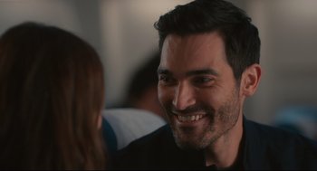 Movie still from “Can You Keep a Secret?” (2019), directed by Elise Durán – A person with a beard smiling; Close Up shot, Over the shoulder angle