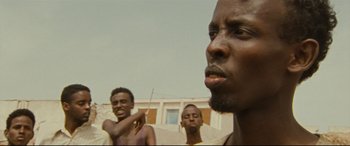 Movie still from “Captain Phillips” (2013), directed by Paul Greengrass – A group of men standing next to each other on top of a building; Close Up shot, Low angle