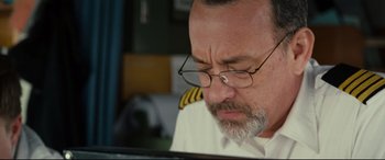Movie still from “Captain Phillips” (2013), directed by Paul Greengrass – An older man wearing glasses looking down at a laptop computer; Close Up shot, High angle