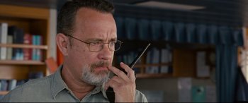 Movie still from “Captain Phillips” (2013), directed by Paul Greengrass – An older man with glasses is talking on a cell phone; Close Up shot, High angle
