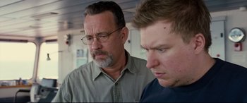 Movie still from “Captain Phillips” (2013), directed by Paul Greengrass – A man and a man looking at each other in front of a window; Close Up shot, Low angle