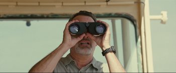 Movie still from “Captain Phillips” (2013), directed by Paul Greengrass – A man looking through a pair of binoculars; Close Up shot, Low angle