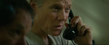 Movie still from “Captain Phillips” (2013), directed by Paul Greengrass – An older man talking on a phone while wearing a white shirt; Close Up shot, High angle