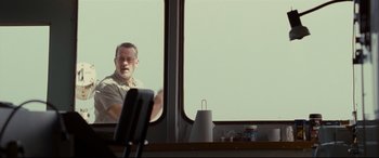 Movie still from “Captain Phillips” (2013), directed by Paul Greengrass – A man sitting in front of a large window; Medium shot, Over the shoulder angle