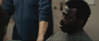 Movie still from “Captain Phillips” (2013), directed by Paul Greengrass – A man sitting in front of another man in front of a mirror; Close Up shot, Over the shoulder angle