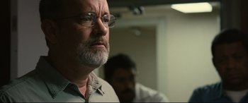 Movie still from “Captain Phillips” (2013), directed by Paul Greengrass – An older man with a beard and glasses looking into the distance; Close Up shot, Low angle