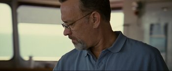 Movie still from “Captain Phillips” (2013), directed by Paul Greengrass – A person wearing glasses and a blue shirt; Close Up shot, Low angle