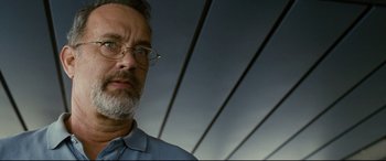 Movie still from “Captain Phillips” (2013), directed by Paul Greengrass – A person wearing glasses and a blue shirt; Close Up shot, Low angle