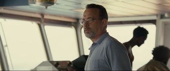 Movie still from “Captain Phillips” (2013), directed by Paul Greengrass – A man with glasses is standing in front of a window; Close Up shot, Over the shoulder angle