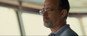 Movie still from “Captain Phillips” (2013), directed by Paul Greengrass – An older man wearing glasses and a blue shirt; Close Up shot, Low angle