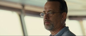 Movie still from “Captain Phillips” (2013), directed by Paul Greengrass – An older man with a beard wearing glasses; Close Up shot, Over the shoulder angle