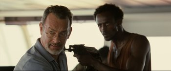 Movie still from “Captain Phillips” (2013), directed by Paul Greengrass – A man holding a gun next to another man; Close Up shot, Over the shoulder angle