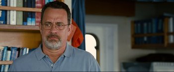 Movie still from “Captain Phillips” (2013), directed by Paul Greengrass – An older man wearing glasses standing in front of an american flag; Close Up shot, Over the shoulder angle