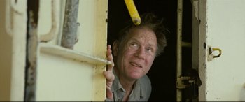 Movie still from “Captain Phillips” (2013), directed by Paul Greengrass – A man holding a ruler up to his head; Close Up shot, Low angle