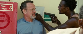 Movie still from “Captain Phillips” (2013), directed by Paul Greengrass – An older man getting a gun fixed by a younger man; Close Up shot, Over the shoulder angle