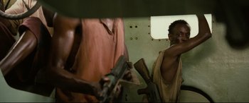 Movie still from “Captain Phillips” (2013), directed by Paul Greengrass – A man holding an ak - 4 7 rifle in his hand; Medium shot, Low angle