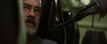 Movie still from “Captain Phillips” (2013), directed by Paul Greengrass – An older man with glasses is holding a rifle; Close Up shot, Low angle