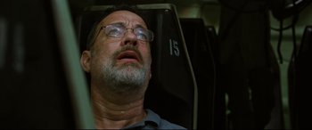 Movie still from “Captain Phillips” (2013), directed by Paul Greengrass – An older man with glasses sitting in a chair; Close Up shot, Low angle