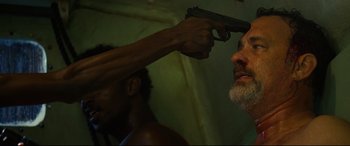 Movie still from “Captain Phillips” (2013), directed by Paul Greengrass – A man holding a gun up to his head; Close Up shot, Over the shoulder angle