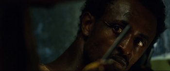 Movie still from “Captain Phillips” (2013), directed by Paul Greengrass – A man holding a knife; Extreme Close Up shot, Over the shoulder angle