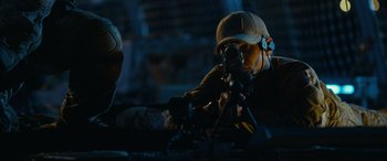 Movie still from “Captain Phillips” (2013), directed by Paul Greengrass – A man wearing a helmet is working on a machine gun; Medium shot, Low angle