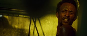 Movie still from “Captain Phillips” (2013), directed by Paul Greengrass – A man standing next to a yellow wall; Close Up shot, Low angle