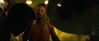 Movie still from “Captain Phillips” (2013), directed by Paul Greengrass – A man in a brown tank top is standing in the dark; Close Up shot, Low angle