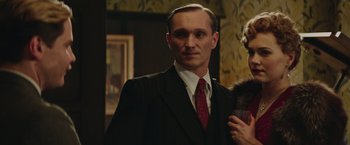 Movie still from “The Zookeeper's Wife” (2017), directed by Niki Caro – A man wearing a suit and tie standing next to a woman; Medium shot, Low angle