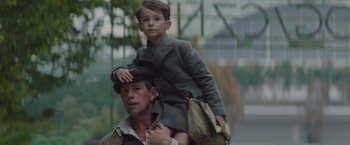 Movie still from “The Zookeeper's Wife” (2017), directed by Niki Caro – A man carrying a child on his shoulders; Medium shot, Low angle
