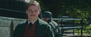 Movie still from “The Zookeeper's Wife” (2017), directed by Niki Caro – A man with a mustache wearing a suit and tie; Close Up shot, Low angle